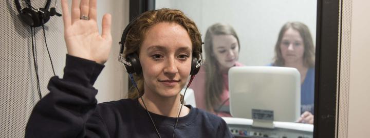 Communication science and disorders students testing a subject's hearing in a mock lab setting.